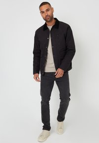 Czarna, zapinana na guziki kurtka z sztruksowym kołnierzem, w połączeniu z beżową koszulą, czarnymi dżinsami i off-white trampkami. Prosty i nowoczesny design.