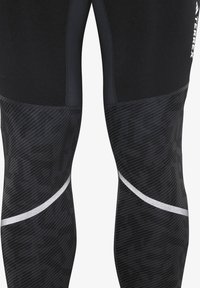 Black athletic leggings with textured pattern and a sleek, fitted design. Features glossy silver accents and flatlock seams for comfort.