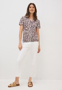 Blusa de manga corta en blanco con un estampado de leopardo en color marrón, con escote en forma de V. Combinada con pantalones blancos ligeramente recortados y sandalias de tiras en color beige.