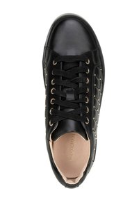 Black sneaker with a smooth leather exterior, quilted pattern, gold eyelets, and black laces. Beige interior visible at the opening.