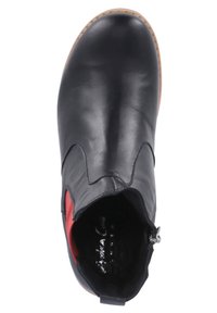 Botín negro de cuero con textura suave, diseño superior asimétrico y acento rojo. Cuenta con un cierre lateral de cremallera y suela de goma.