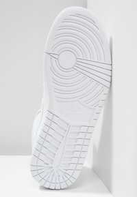 Vitt sneaker sula med djupa spår, cirkulära mönster och en texturerad yta med en inpräglad logotyp på sidan.