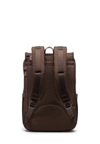 Zaino in tessuto marrone con spallacci imbottiti, maniglia superiore, cerniere laterali e una texture liscia. Ha una forma rettangolare compatta.