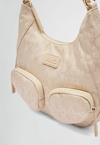 Borsa a spalla beige chiaro realizzata in materiale testurizzato, con un sottile motivo a logo, due tasche frontali con zip e hardware color oro.