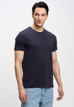 Camiseta de cuello redondo azul marino de tela suave, con mangas cortas, corte ajustado, combinada con vaqueros de mezclilla azul claro. Diseño simple y minimalista.
