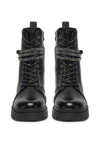 Czarne skórzane buty wojskowe z grubymi podeszwami, sznurowadłami i ozdobnymi, owijającymi się wokół paskami z kryształków, pokazane od przodu na białym tle.