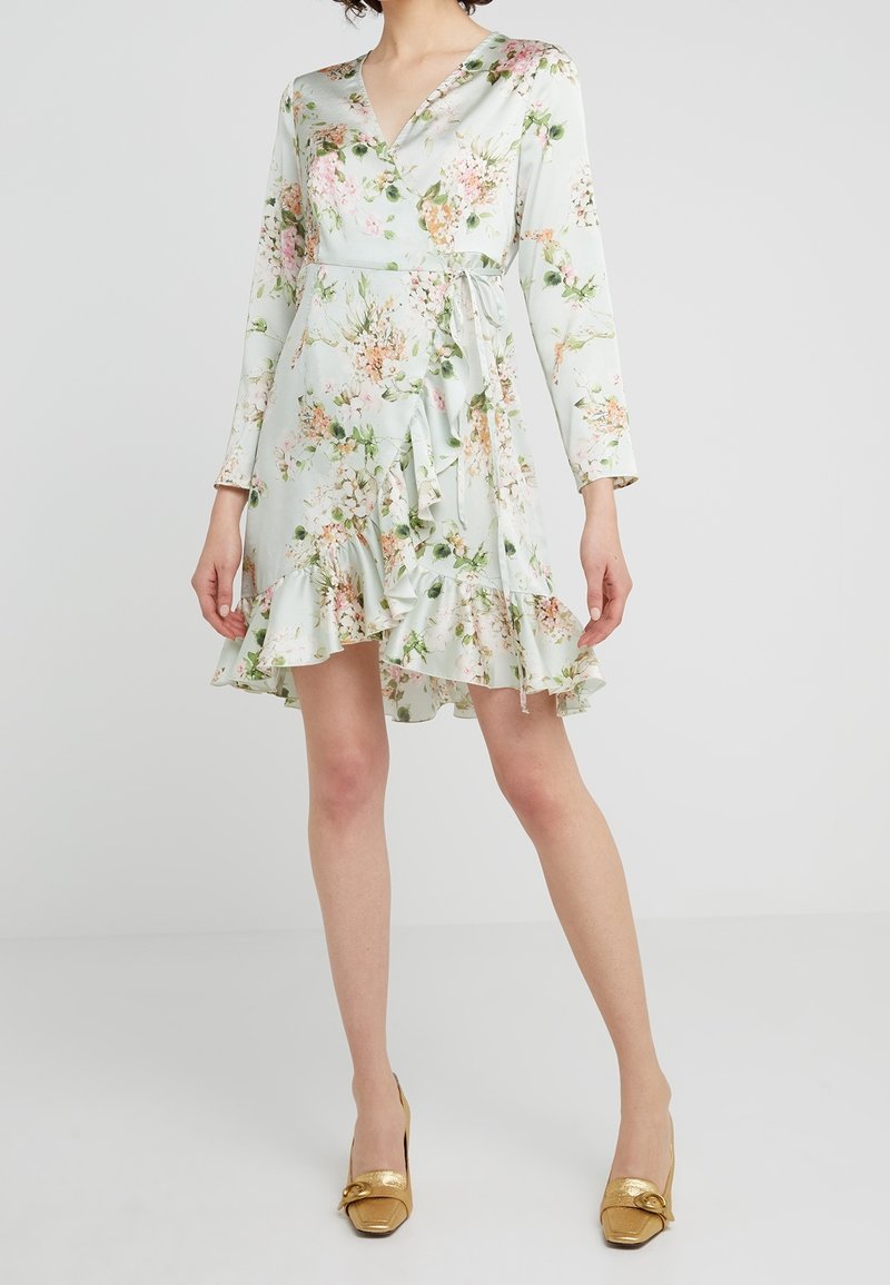 Vestito avvolgente floreale di colore verde chiaro con maniche lunghe, orlo a volant e vita con fiocco. Caratterizzato da una stampa di fiori rosa e arancioni su un tessuto liscio.