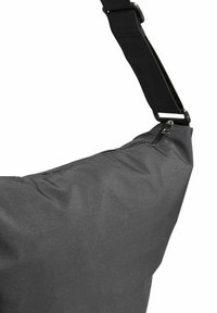 Juodas audinio peties krepšys su užtrauktuku, kampuota forma ir reguliuojama juosta. Pasižymi lygiu paviršiumi ir minimalistiniu dizainu.