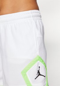 Λευκές αθλητικές βερμούδες με υφή, με πράσινη λεπτομέρεια στο πλάι και μαύρο λογότυπο Jordan. Ελαστική μέση για καλύτερη εφαρμογή.
