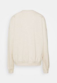 Sudadera de color crema con un corte relajado, mangas largas y puños y dobladillo acanalados. La tela tiene una apariencia suave y texturizada.
