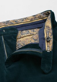 Groene corduroy broek met een voering met bloemenpatroon, een messing rits en knoopsluiting. Gedetailleerde naden versterken het gestructureerde ontwerp.