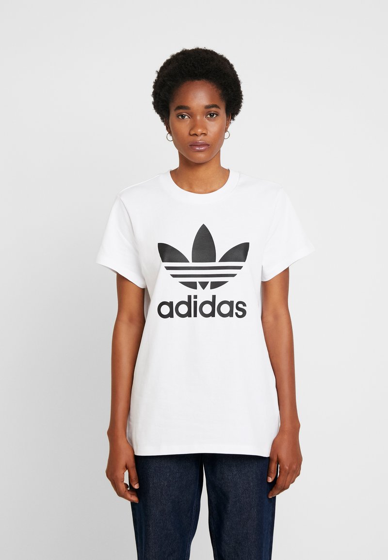 Bílá bavlněná tričko s černým logem Adidas a klasickým trojlístkovým designem. Krátké rukávy a kulatý výstřih.