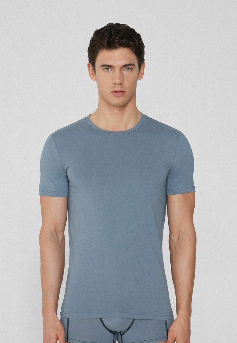 Camiseta de manga corta azul claro en un diseño ajustado, hecha de un tejido suave. Presenta un escote redondo y detalles de costura mínimos.