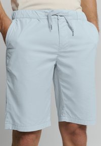 Lichtblauwe, knielange shorts gemaakt van lichtgewicht, gestructureerde stof. Voorzien van een elastische tailleband met een trekkoord en zijzakken.