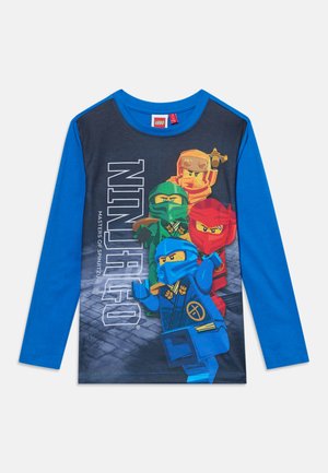 Chemise bleue à manches longues avec des personnages LEGO Ninjago en rouge, bleu, vert et orange à l'avant avec le texte "NINJAGO" en vertical.