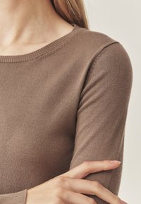 Convers gebreide, lange mouwen sweater met een ronde hals, gemaakt van zachte, geribbelde breizijde. Beschikt over aansluitende mouwen en een gladde textuur.