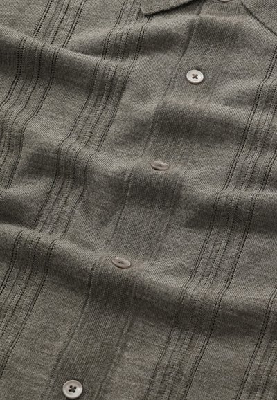 Grijze gebreide shirt met een gestructureerd patroon, voorzien van verticale strepen, een puntkraag en lichtgekleurde knopen. Zachte en ademende stof.