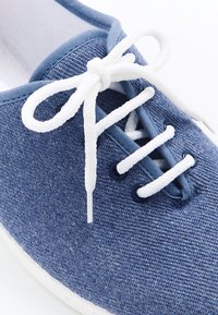Sneaker in tessuto blu con lacci bianchi, dotato di tomaia testurizzata, punta rotonda e suola in gomma. Include passanti in contrasto e dettagli dei lacci.