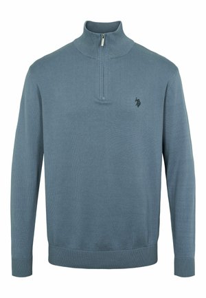 Lichtblauwe trui met een hoge kraag, halve rits en geribde manchetten en Zoom. Bevat een klein zwart logo op de borst. Zachte gebreide textuur.