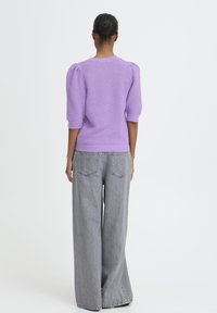 Lavendelfarbener Strickpullover mit strukturierter Oberfläche, Puffärmeln und geripptem Saum, kombiniert mit grauen Jeans mit weitem Bein. Einfaches, modernes Design.