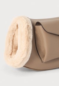Borsa in pelle marrone chiaro con rifiniture in pelliccia morbida beige chiaro. Ha una forma strutturata ed è accentuata da dettagli di cucitura visibili.