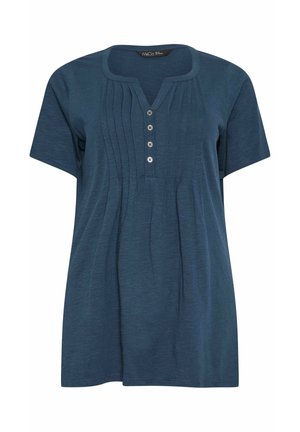 Niebieska bluzka z krótkim rękawem, z okrągłym dekoltem z wycięciem, cztery guziki z przodu oraz pionowe plisy na wysokości klatki piersiowej.