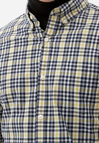 Camicia a quadri con bottoni, nei colori blu navy, bianco e giallo. Realizzata in cotone, con taschino sul petto e collo classico.