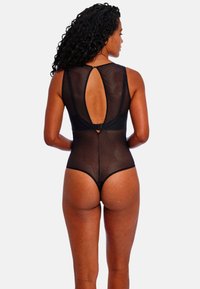Body negro semitransparente con textura de puntos, que presenta un diseño de espalda con escote en forma de llave y una silueta ajustada. Minimalista con sutiles acentos metálicos.