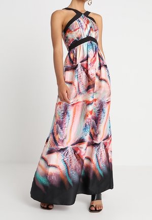 Ärmelloses Maxikleid mit Neckholder und buntem abstraktem Muster, schwarzer Einfassung und fließendem Rock, kombiniert mit schwarzen, offenen Schuhen.