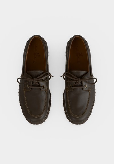 Paire de mocassins bateau en cuir brun foncé avec lacets à l'avant et détails cousus, vue de dessus sur un fond clair.