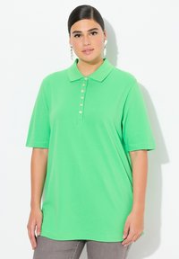 Zielona koszulka polo z kołnierzykiem i zapięciem na guziki. Krótkie rękawy, luźny krój, wykonana z miękkiego, gładkiego materiału.