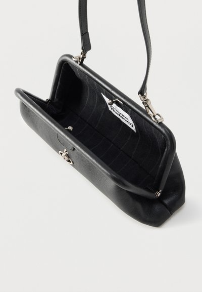 Μαύρη δερμάτινη τσάντα ώμου με ασημένιο κούμπωμα, ανοιχτή, που δείχνει εσωτερικό από μαύρο ύφασμα και μικρή λευκή ετικέτα στο εσωτερικό.