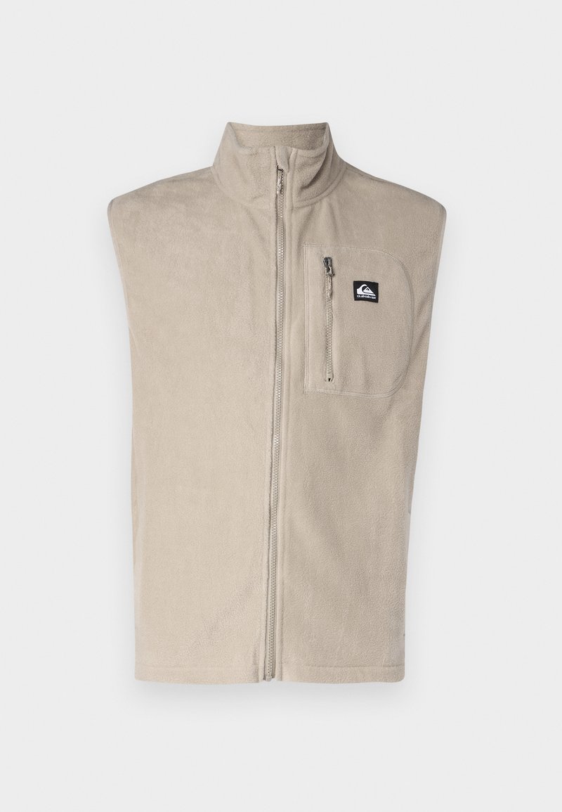 Chaleco de forro polar beige con cierre de cremallera, cuello alto y un único bolsillo en el pecho con cremallera. Textura suave y diseño sin mangas.