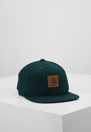 Ciemnozielona materiałowa czapka baseballowa z płaskim daszkiem i brązową kwadratową naszywką z logo Carhartt z przodu, położona na białej powierzchni.