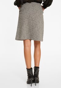 Grijze houndstooth rok met een vloeiende silhouet, voorzien van een ritssluiting aan de achterkant. Gepaard met zwarte enkellaarsjes met een puntige neus.