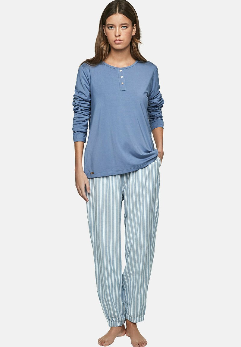 Haut à manches longues bleu clair avec patte de boutonnage, associé à un pantalon de pyjama rayé bleu clair et blanc, doté d'un poignet élastique à la cheville.