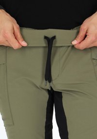 Groene herenbroeken met een trekkoord in de taille, voorzien van zwarte accenten en een gestructureerde stof. Inclusief zakken en een gestroomlijnd ontwerp.