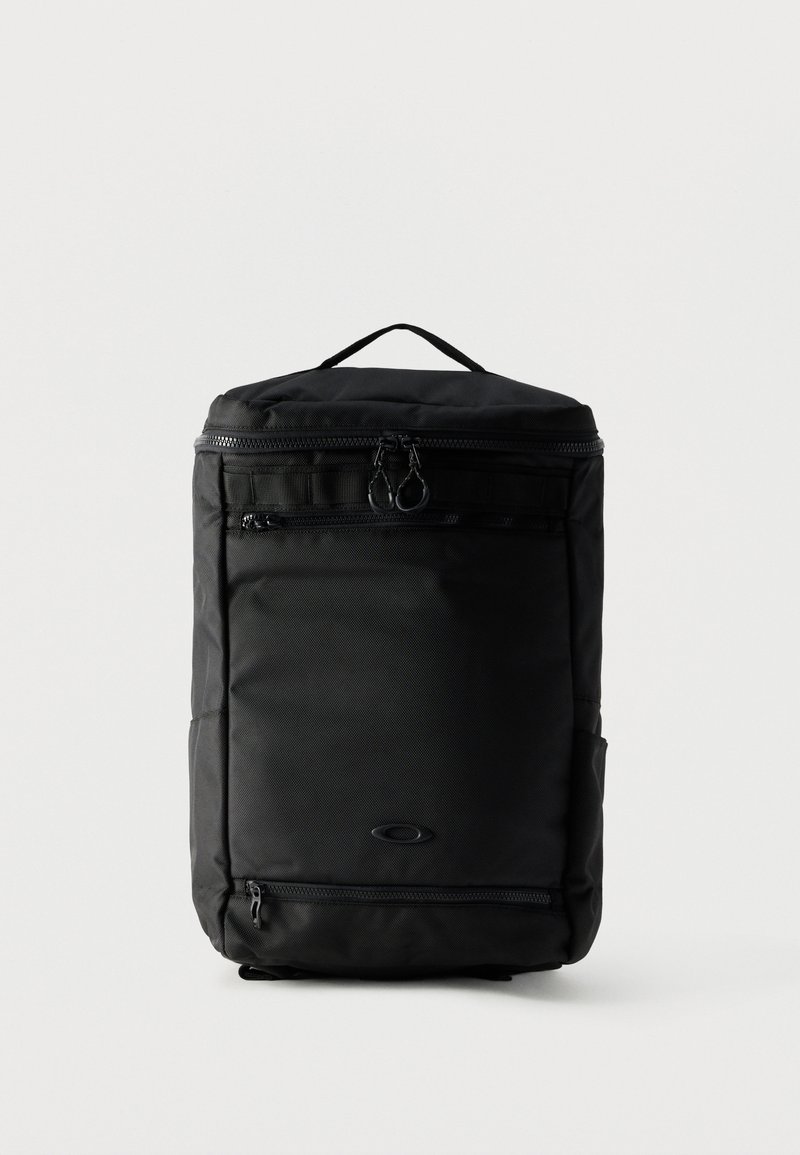 Sac à dos rectangulaire noir avec poignée supérieure, poches avant zippées et fermeture à double zip arrondie du compartiment principal.