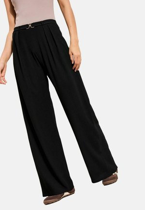 Fekete, bő szárú nadrág függőleges bordázattal és magas derékkal. Aranyszínű övcsatt díszíti, oldalzsebekkel.