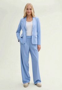 Light blue tailored blazer and matching wide-leg trousers, crafted from smooth fabric. Features two front pockets and a classic lapel design.