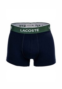 Boxer in cotone blu navy con cintura elastica verde con il marchio e logo bianco "LACOSTE". Design aderente con un taglio tipico da boxer.