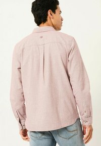 Langarmhemd in hellrosa mit strukturiertem Muster, Button-down-Kragen und Zweiknopfmanschetten. Verfügt über eine mittige Rückenfalte.
