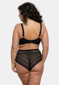 Ensemble en dentelle noire comprenant un soutien-gorge et un slip taille haute. Le soutien-gorge dispose de bretelles réglables et d'un design texturé, tandis que le slip présente des motifs géométriques.