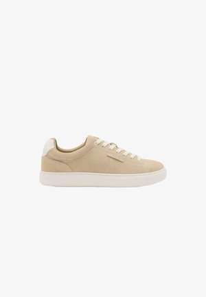 Beige suède lage sneaker met witte veters, witte zool en witte hieltab, zijaanzicht op een witte achtergrond.