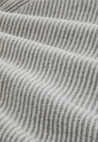 Tessuto a righe grigie e bianche con una texture morbida, caratterizzato da strisce spesse e sottili alternate in un motivo ondulato.