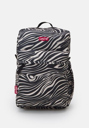 Le sac à dos zebré noir et blanc de Levi's dispose d'un compartiment principal rembourré, d'une poche zippée à l'avant et d'une poignée de transport en haut.