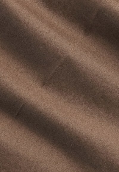Gros plan sur un tissu marron avec des plis diagonaux et des ombres douces créant un motif texturé.