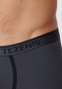 Boxer de color gris oscuro con una textura suave y una cinturilla elástica negra con el logo "TEZENIS" en un diseño sutil grabado.