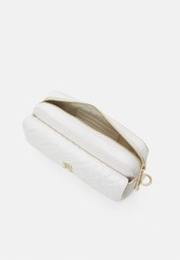 Hvid læderpouch med et tekstureret quiltet design, gylden lynlås og metaldele. Har et rummeligt hovedrum og en slank silhuet.