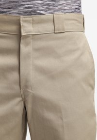 Beige bomuldsbukser med en glat tekstur, der har en lige pasform, flad frontdesign og en standard talje med bæltesløjfer.
